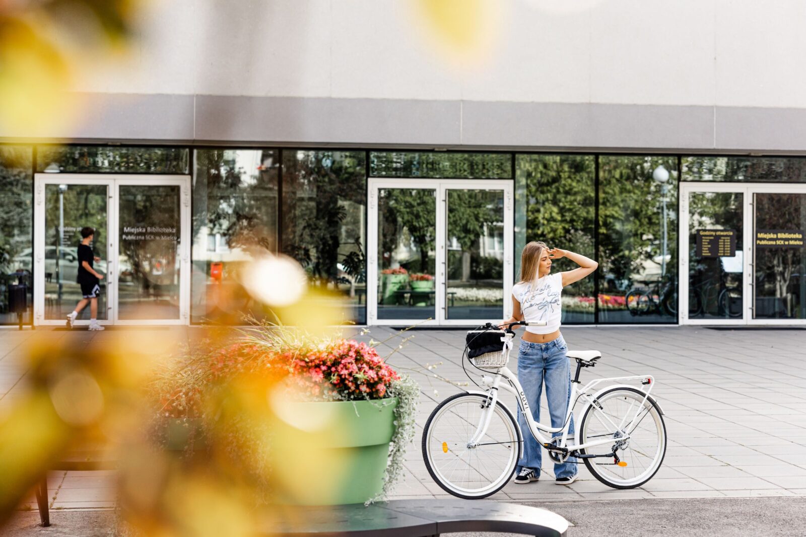 Kvinna vid cykel utanför en modern byggnad.
