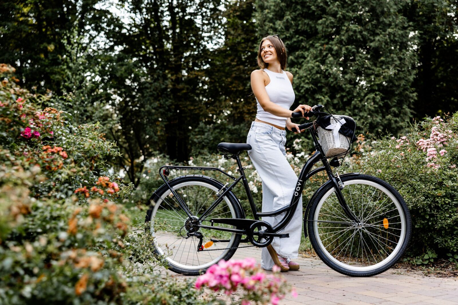 Kvinna med cykel i blommande trädgård