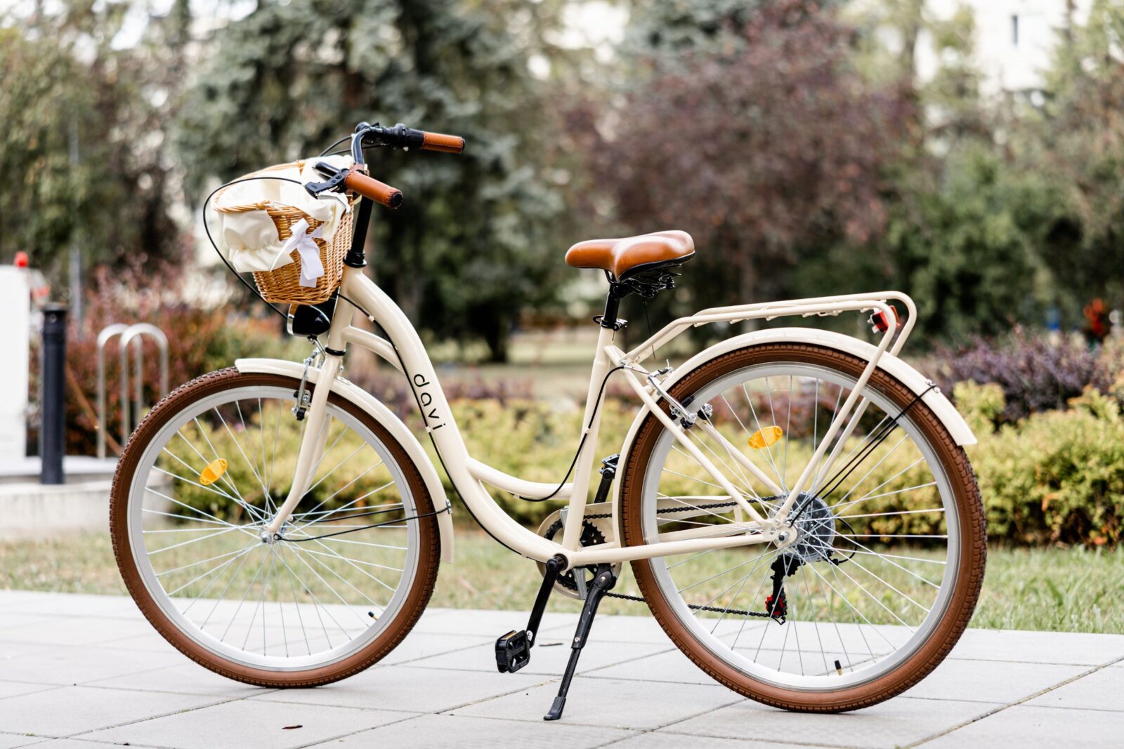 Klassisk beige cykel med korg på trottoaren.