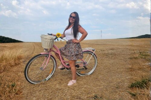 Žena na růžovém kole v poli.